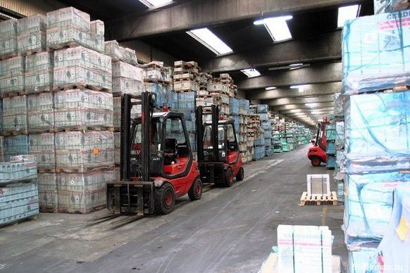 Forklifts moving pallets of tile along the loading aisle of the warehouse